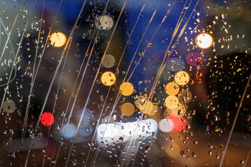 Wall Mural - Selective focus at scratch and rain drops on glass of back of vehicle with blur night view with golden bokeh of street.