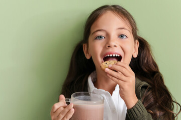 Little girl with tasty chocolate milk and cookie on color background