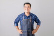 © SKT Studio - Asian man in barista uniform standing in studio isolated on grey background
