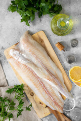 Wall Mural - Cod fillet. Raw cod fillet on a chopping Board on a light gray kitchen table. Preparation for cooking fish. Top view	