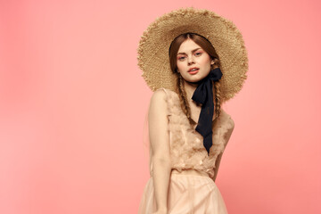 Fashionable woman in dress and hat with black ribbon on pink background cropped view of model emotions fun