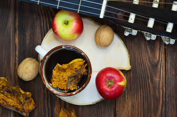 Cozy autumn evening at home with a cup of hot coffee and a guitar, walnuts, apple, healthy organic food concept