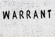 Inscription warrant painted on white brick wall