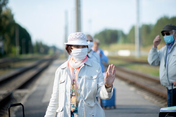 Wall Mural - Positive elderly seniors people with face masks waiting train before traveling during a pandemic