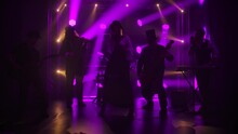 The Band In Original Irish Costumes And Hats Perform In A Dark Studio Against A Backdrop Of Dynamic Purple Lights. Slow Motion.