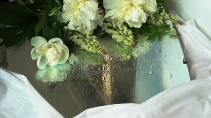 Canvas Print - A white flower with green leaves falls on a wet mirror