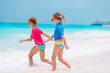 © travnikovstudio - Two little happy girls have a lot of fun at tropical beach playing together
