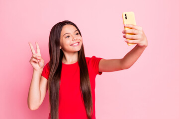 Poster - Photo of lovely sweet little lady long hairstyle raise hand hold telephone show v-sign take selfie video message look screen wear casual red t-shirt isolated pink color background