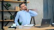© viacheslav - Tired man massages neck after using laptop computer long time, poor posture requiring treatment. Male student studying remotely online by video call conference web cam, distance education
