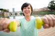 © Davide Angelini - Senior woman training gym work out holding dumbbells. Portrait of a mature woman doing fitness exercise at the park. Senior people and sport concept.
