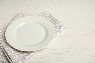 Empty plate and napkin on white wooden table