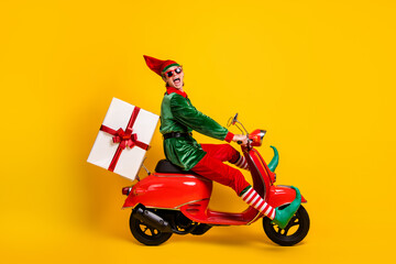 Canvas Print - Profile side view of his he nice attractive cheerful cheery crazy funny guy elf riding moped delivering giftbox Eve Noel fairy isolated over bright vivid shine vibrant yellow color background