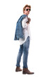 © sharplaninac - Stylish handsome man carrying jeans jacket looking at camera over the shoulder. Side view. Full body isolated on white background.