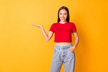 Canvas Print - Photo of attractive lady hold open palm presenting novelty wear casual red top jeans isolated over yellow color background