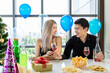 © wirojsid - Attractive young male and female celebrate Christmas and New Year in office party, man give glass of wine to woman