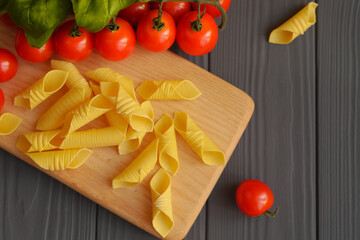 Branch of cherry tomatoes and Garganelli pasta on a wooden table