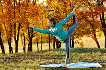 Woman Practicing Yoga One Leg Stand In The Autumn Park