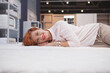 © mad_production - Cheerful lovely woman enjoying lying on a new bed on sale at furniture store