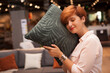 © mad_production - Charming young woman trying soft cushion, shopping at furnishings store