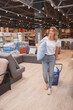 © mad_production - Vertical full length shot of a mature woman carrying pillow, shopping at furniture store
