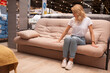 © mad_production - Full length shot of a female customer sitting on a couch, examining it before buying, copy space