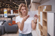 © mad_production - Female customer reading the price tag while shopping for new furniture