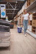 © mad_production - Vertical full length shot of a mature woman walking in furniture store with her cart, enjoying shopping