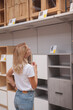 © mad_production - Vertical shot of a female customer looking at shelves and cupboards on sale at furniture store