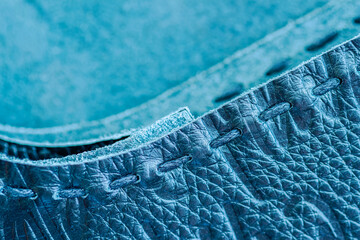 Texture of blue genuine leather sewn with hand made sewing stitch. For fashionable modern background