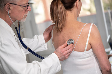 Senior doctor using stethoscope to exam patient