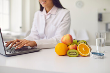 Fruit, a glass of water and a tape measure lie on the table against the background of a nutritionist