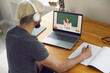 © Studio Romantic - Online education. A young man sitting at a table at home using a laptop and a video call to listen to a lesson online.