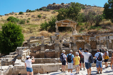 ourists look at the ruins in the ancient Greek city Ephesus or Efes on the coast of Ionia in Izmir Province, Turkey in summer day