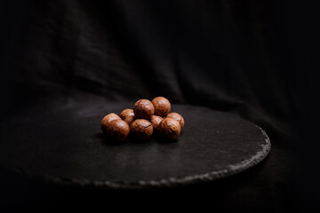 Macadamia nuts in their shells on an empty dark background