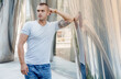 © ibilyk13 - A young man leans on a shiny column. Courageous guy with a firefighter tattoo on his biceps. Male portrait.