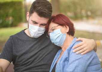 mother and son tenderly hugging. mother and son in medical mask portrait.