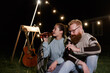© vladdeep - Friends having fun on the night picnic with drinks. Young caucasian couple at bbq in countryside