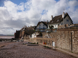 Local vintage historical cottage houses with straw roofing and high stone walls by the seaside beach