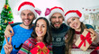 © My Ocean studio - Happy group of excited beautiful friends in Santa hats are having fun while partying at home on the Christmas tree background