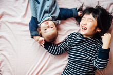 Little Girl Playing With Her Baby Brother On Bed