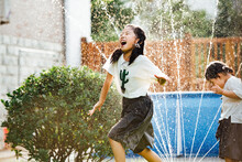 Little Girl In Backyard Enjoyment With Garden Sprinkler