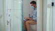 © america_stock - Happy businessman working on laptop wearing mask sit on the toilet at home restroom bearded funny wc isolation quarantine pandemic coronavirus covid-19 portrait close up slow motion