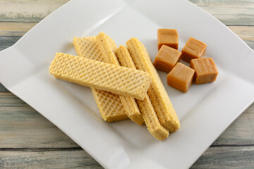 Wall Mural - Caramel wafer cookies with caramel candy squares on white dessert plate