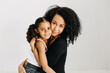 © Kristen Curette Photography LLC/Stocksy - A studio photograph of an African American mother and daughter embracing / hugging.