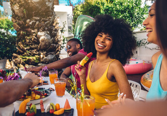 Group friends having fun drinking cocktails sitting in villa backyard - Happy young hispanic woman smiling at the camera at garden party with friends - Summer lifestyle and food concept.