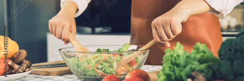 Fotografía Asian woman is mixing the ingredients in a salad bowl at the kitchen cooking table