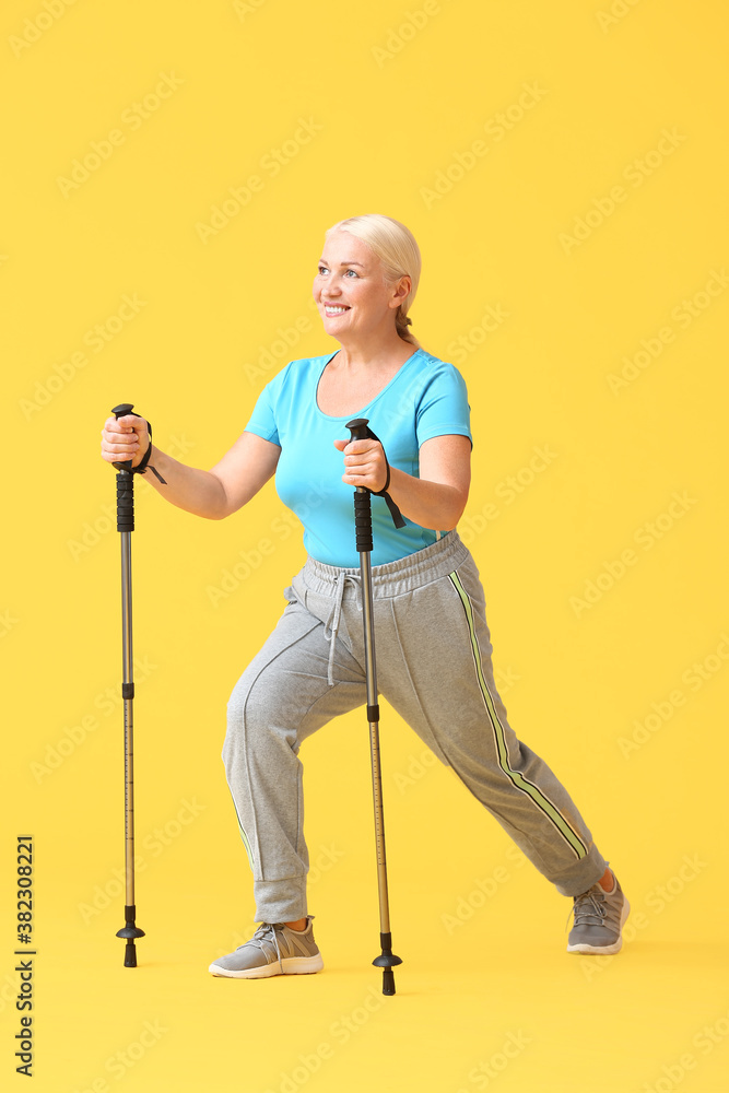 Mature woman with walking poles on color background