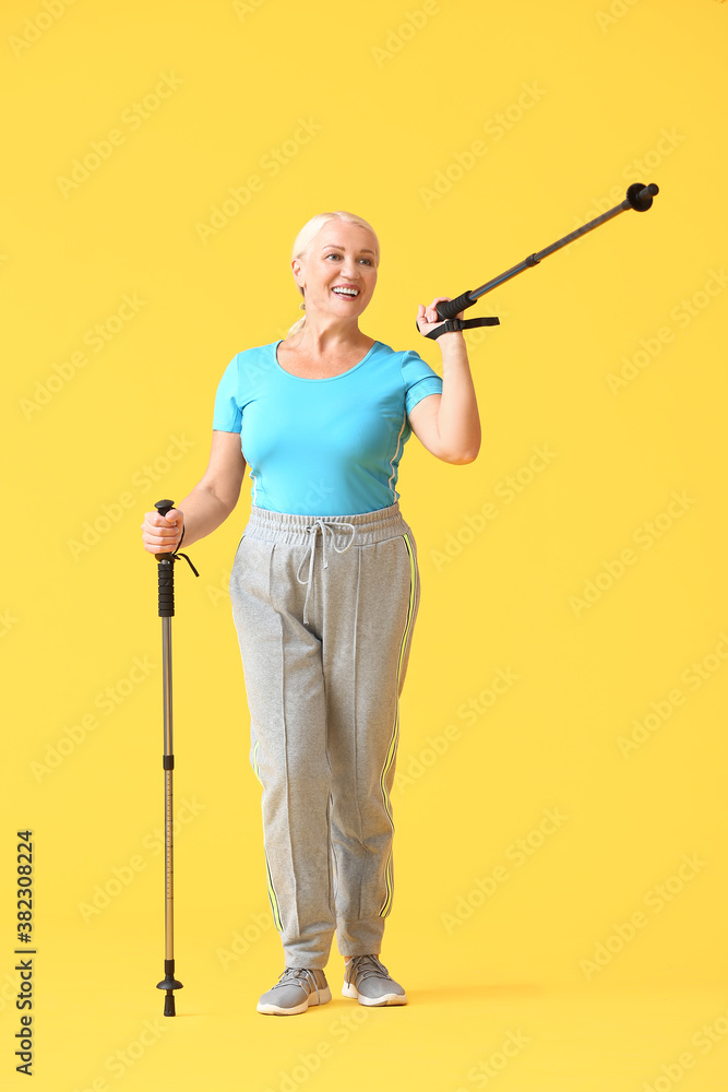 Mature woman with walking poles on color background