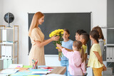 Fototapeta  - Schoolchildren greeting their teacher in classroom