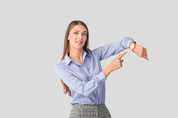 Wall Mural - Young woman with wristwatch on light background